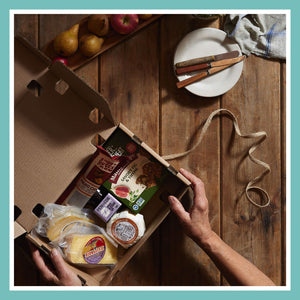 Open gift box with handcrafted cheeses and gourmet snacks